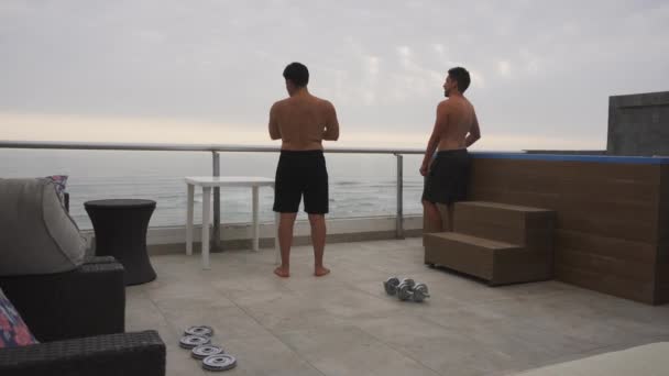 Two Friends Looking Horizon Exercising Dumbbells Terrace Beach House Swimming — ストック動画