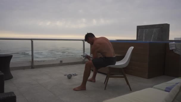 Mężczyzna Siedzący Tarasie Domku Plaży Basenem Morzem Tle Mijający Mewę — Wideo stockowe