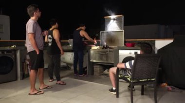 Bir kaç arkadaş gece arkadaşlarıyla birlikte bir sahil evinin çatısında sigara içip et kesiyorlar.