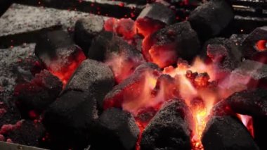 Yakın plan karıştırıcı altıgen şekilli kömür kömürleri, tahta bir sopayla ızgaranın etrafında ateş, kıvılcımlar ve gecenin 4 'ünde küller yükseliyor.