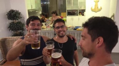 Arkadaşların bira içtiği selfie ve arka planda 4K 'de yemek yapan ve kameraya el sallayan kadınlar.