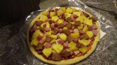 Ev yapımı pizzaya et ve peynir ekleyerek ve mutfakta ellerinle hazırlayarak.