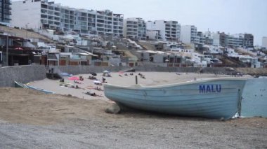 Punta Hermosa, Lima, Peru 'daki Senyoritas plajı. Balıkçı tekneleri ve tanınmayan insanlarla dolu. Gün içinde şemsiyelerle kumsalda güneşleniyorlar.