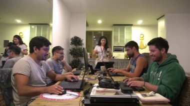 Kadınlar yemek odasında laptoplarıyla oynayan arkadaşlarına bira veriyor.