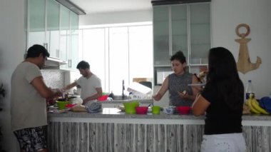 Gündüz vakti mutfakta ev yapımı Meksika tacoları yiyen birkaç erkek ve kadın arkadaş.