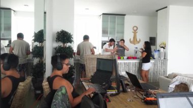 Bazı erkek ve kadın arkadaşlar mutfakta yemek yerken, bir arkadaş da gün içinde merkez büroda yemek odasında çalışıyor.