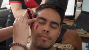 Peru bayrağı taşıyan bir adamın yüzünü, futbol maçından önce arkadaşlarıyla birlikte 4K 'da yapılan bir futbol maçından önce bir işaret olarak resmetmek.