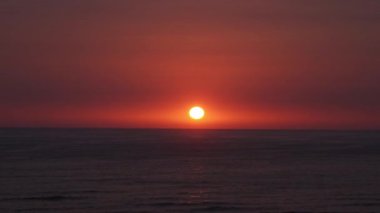 Güneşin parlak sarı yuvarlak güneşiyle güzel bir günbatımının küçük bir kamerası denizin ufkunda gökyüzü ile birlikte saklanıyor. Punta Hermosa, Lima, Peru 'daki Playa Senoritas' ta zaman aşımı.