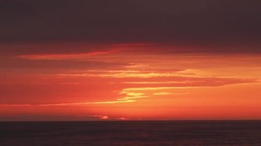 Turuncu gökyüzü ile deniz üzerinde sarı bir fırçayla boyanmış ve çizilmiş gibi görünen bir gün batımı