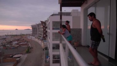 Bir sahil evinin terasında bir düğün çifti gelip giden bir arkadaşı tarafından rahatsız ediliyor.