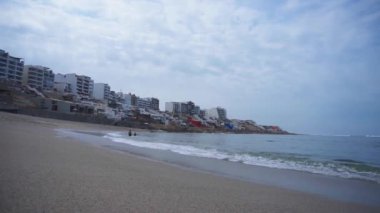 Tanınmayan bir çift gündüz vakti denizin dalgalarıyla oynuyorlar. Punta Hermosa, Lima, Peru 'daki sahilde bir kadın ve bir erkek.