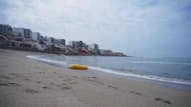 Sahilde sarı muz şeklinde bir şamandıra Punta Hermosa, Lima, Peru 'daki Senyoritas sahilinde deniz dalgaları tarafından taşınıyor.