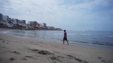 Punta Hermosa, Lima, Peru 'daki Senyoritas plajında kumsalda yürüyen bir adam kameradan uzaklaşıyor.