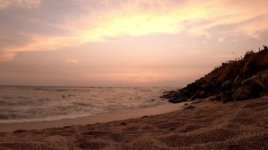 Tanımlanamayan sörfçüler denizden çıkan çocuklar kumsaldan gün batımını ve ufuktaki güneşi güzel bir şekilde görüyorlar.