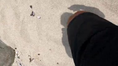 POV sahilin kumsalında koşan zemine bakıyor 4K 'da deniz ile kıyılar arasındaki kayaların üzerinden atlıyor.