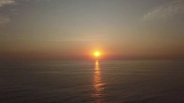 Hızlı hareket eden insansız hava aracı güzel bir günbatımının görüntüsü. Denizin üzerinde hareket ediyor. Güneş suyun üzerinde parlıyor.