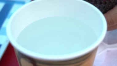 Plastik bardakta sıcak suyla birlikte kahve servisi.