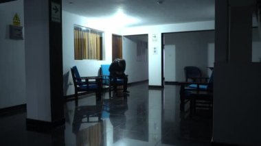 Otelde ortak bir alanda oturan bir adam gece 4K 'de cep telefonuna bakıyor.