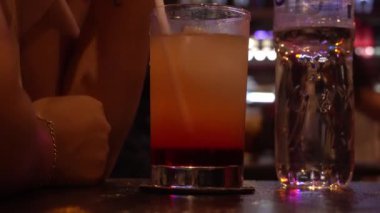 Barda bir kadın tarafından pipetle içilen portakal suyu ile cam bardağa yakın plan.