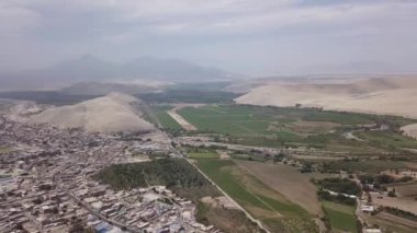 Yanı başında nehirler, tepeler, çöller ve kum tepeleri olan ve Casma, Lima, Peru 'da açık gökyüzü olan bir şehrin insansız hava aracı görüntüsü.