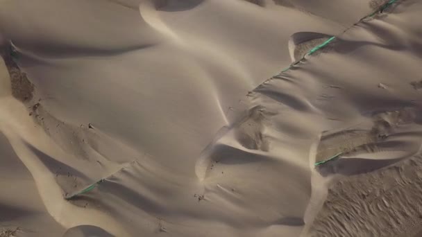 4Kの日に鳥の目のビューで飛んで強い風によって移動砂と砂丘と美しい処女の砂漠の空中ドローンビュー — ストック動画