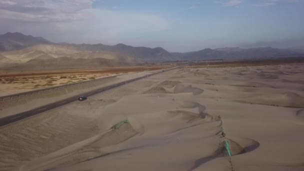 4Kのトラックの外に男と道路の脇に色の山と砂丘がある処女の砂漠の美しい空の景色 — ストック動画