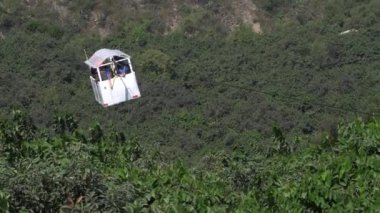 Gündüz dağlarda dağlarla yeşil ağaçlar arasında turistik bir teleferik yolculuğunun keyfini çıkaran çok sayıda insanın yakın çekimi
