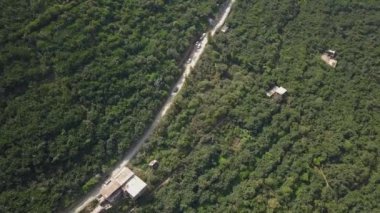 San Mateo de Otao 'nun dağlık bölgelerindeki bir çok yeşil bitki örtüsü arasında gün içinde arabalarla bir patika yolunun hava aracı görüntüsü.