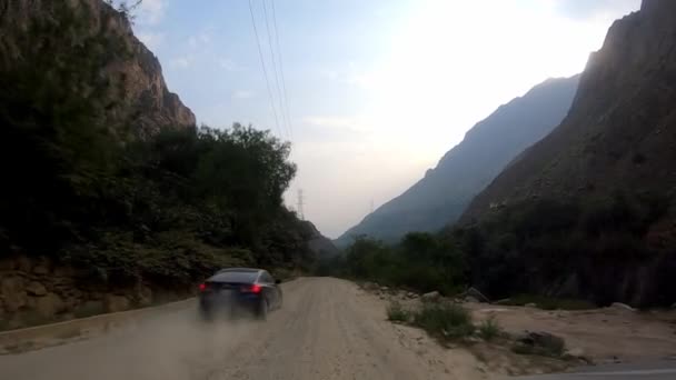 stock video POV driving being passed by a speeding car on a narrow dirt road kicking up dust between bushes with precipice to the side in the highlands with crops, mountains and green trees in point of view