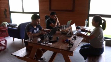 Tatilde bir kır evinde dizüstü bilgisayarlarıyla çalışan ve gün içinde birlikte yemek yiyen birkaç arkadaş.