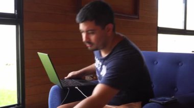 Uzaktan kumandalı bir evde çalışan bir adam dizüstü bilgisayarıyla koltukta oturuyor ve günde 4K ile viski içiyor.