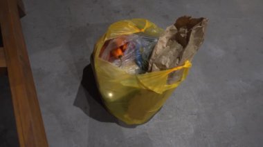 Bir kadın, geceleyin 4K 'da bir kır evinin zemininde, marketten satın aldıklarını elleriyle topluyor.