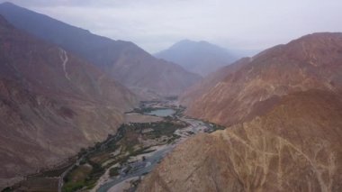 Gündüz vakti Lunahuana 'nın dağlık kesimlerindeki yeşil tarlalar ve dağlar arasındaki güzel ve parçalanmış nehrin insansız hava aracı görüntüsü.
