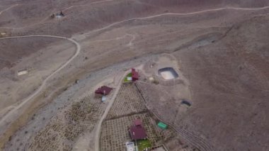 Gündüz vakti Lunahuana 'nın dağlık kesimlerindeki boş bir arazide yüzme havuzlu kır evlerinin insansız hava aracı görüntüsü.