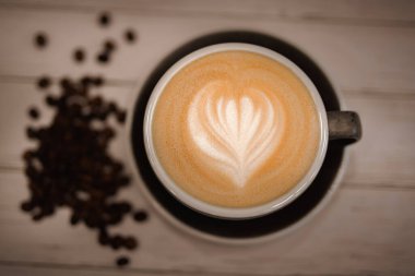 Bir fincan sıcak soya sütlü kahve, ahşap masada kahve, kahve dükkanında da kitap.