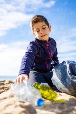 Plajda plastik toplayan küçük bir çocuk. Geri dönüşüm kavramı