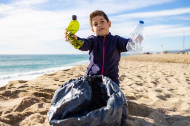 Plajda plastik toplayan küçük bir çocuk. Geri dönüşüm kavramı