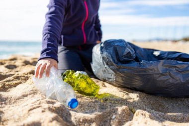 Plajda plastik toplayan küçük bir çocuk. Geri dönüşüm kavramı