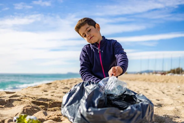 Plajda plastik toplayan küçük bir çocuk. Geri dönüşüm kavramı