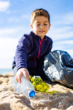 Plajda plastik toplayan küçük bir çocuk. Geri dönüşüm kavramı