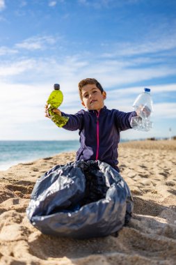 Plajda plastik toplayan küçük bir çocuk. Geri dönüşüm kavramı