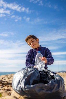 Plajda plastik toplayan küçük bir çocuk. Geri dönüşüm kavramı
