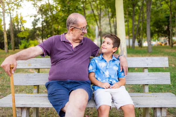 祖父と孫は公園のベンチに座って — ストック写真