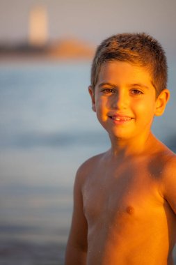 Sahil kenarında oturan sevimli bir çocuğun portresi.