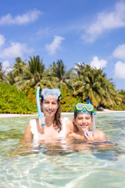 Anne ve oğlu Maldivler Adaları sahilinde şnorkelle yüzüyorlar.