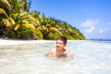 Tropik bir plajda suyun içinde küçük bir çocuk.