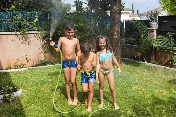 Três Crianças Engraçadas Brincando Com Uma Mangueira Jardim — Fotografia de Stock