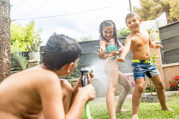 Três Crianças Engraçadas Brincando Com Uma Mangueira Jardim — Fotografia de Stock