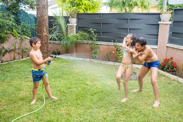 Três Crianças Engraçadas Brincando Com Uma Mangueira Jardim — Fotografia de Stock