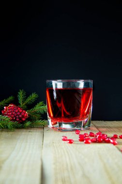 Noel aromalı nar suyu, nar tohumları ve ladin filizi bir bardağa doldurulur. Karanlık bir arka planda vitamin ve mineral suyu. Vücudun temizlenmesi, sağlığa yararlı..